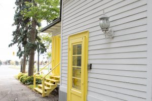 Close-up of white siding, yellow door frame, and lantern light fixture on the GTA office exterior. Caption: Blending history with modern legal practice. Our office preserves the charm of the historic community while serving today’s family law needs across the GTA.